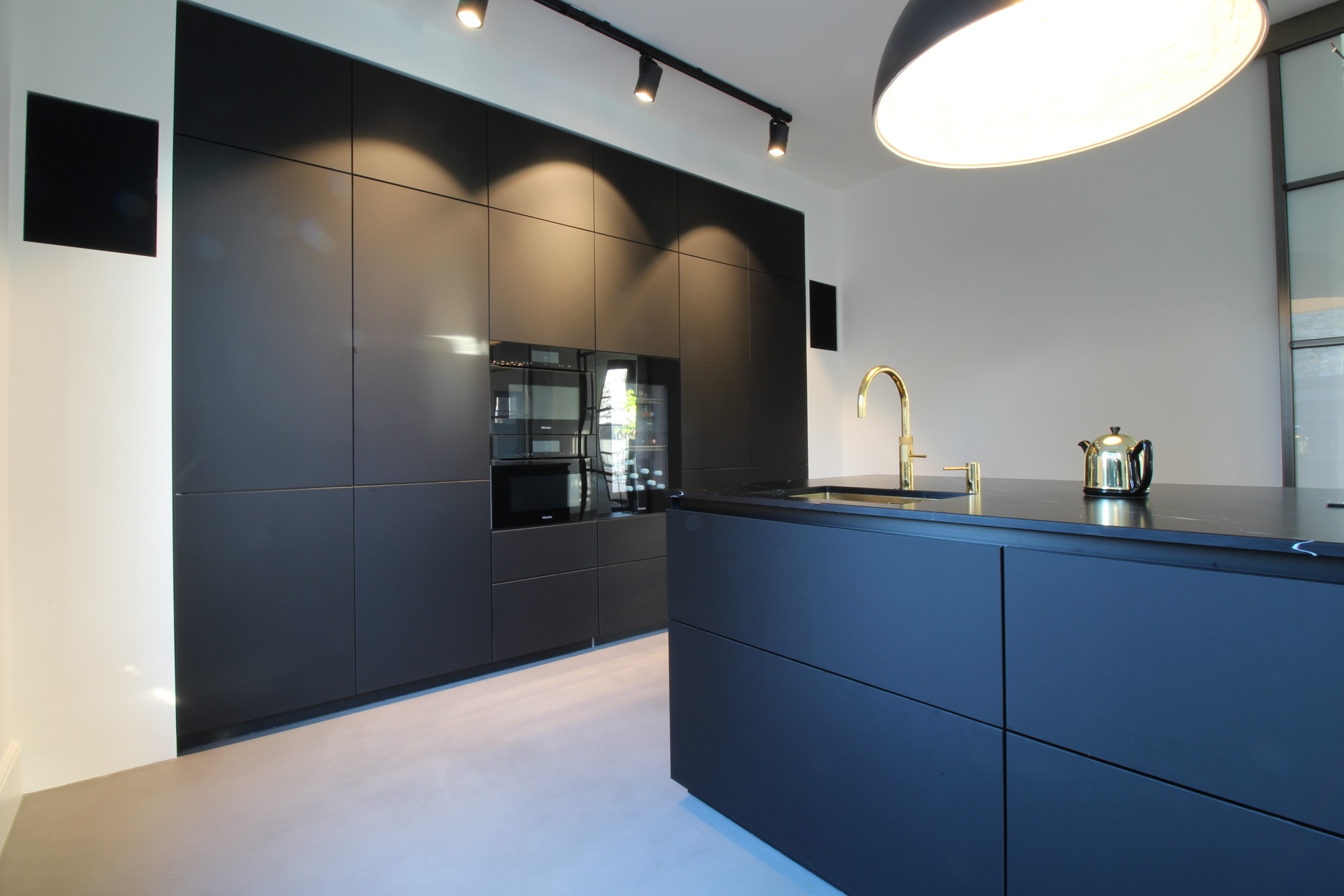 Woonbeton tot wandafwerking in zwarte keuken door Motion
